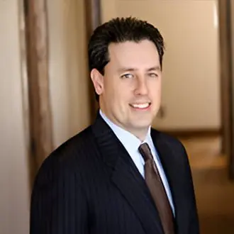 A man in suit and tie standing next to a wall.